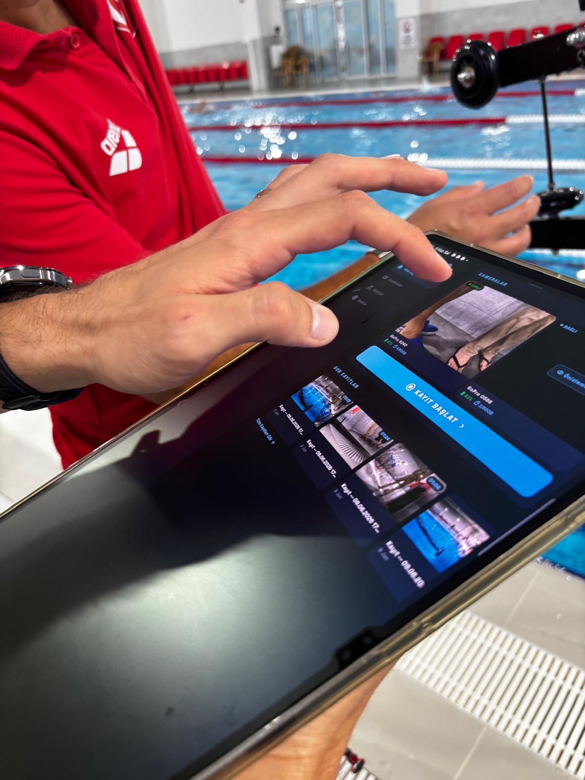 Antrenör havuz kenarında tablette Kulvar uygulamasını kullanıyor